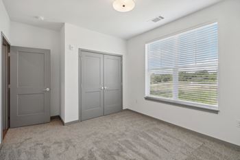 The living room of an apartment with a large window and gray doors